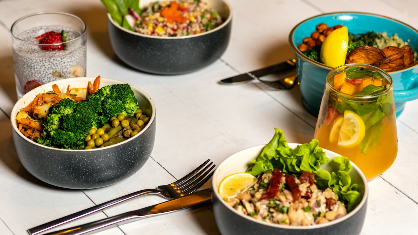 Assortment of healthy meal bowls and drinks on a white table.